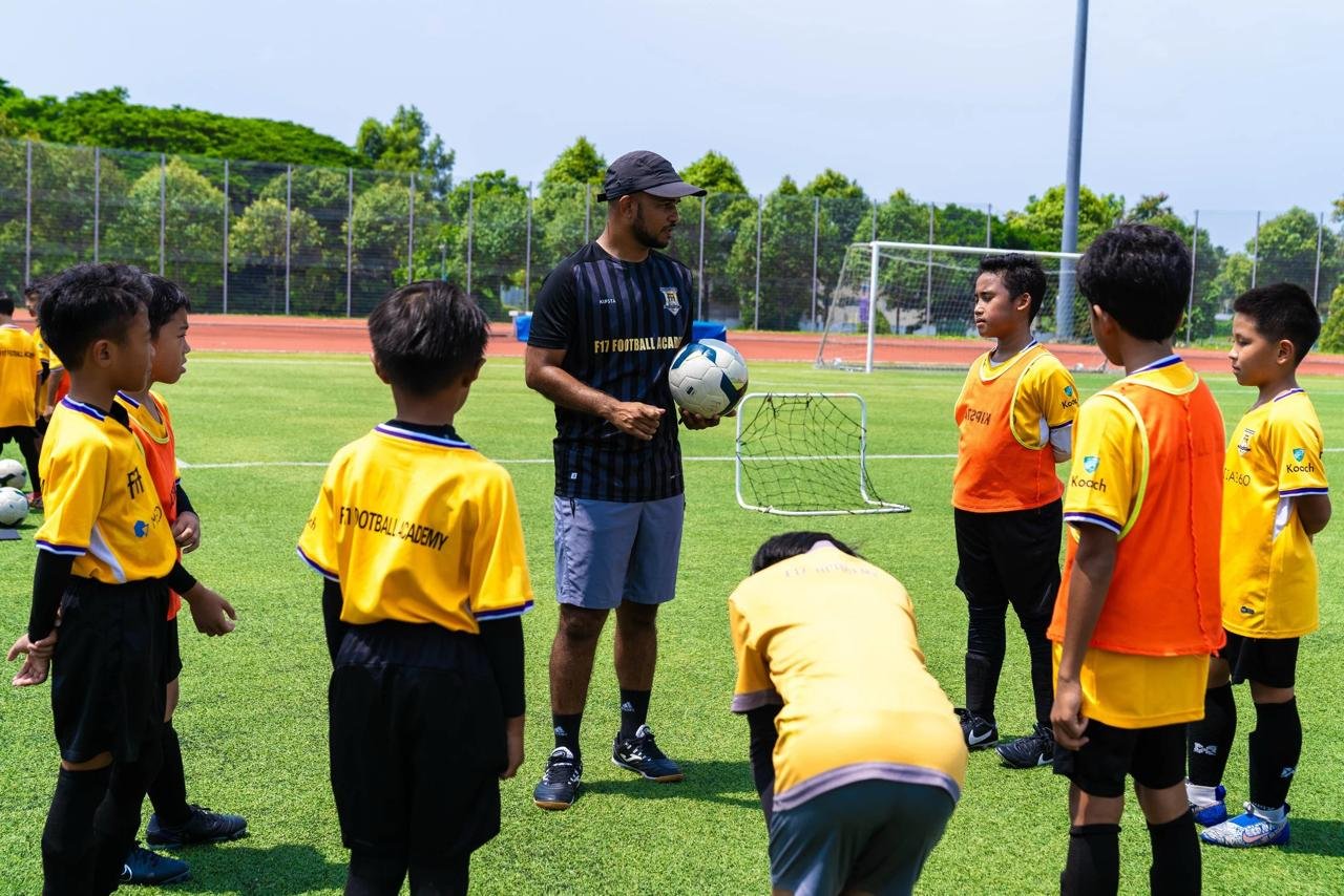 F17 coach guiding young football players through a discovery-based activity